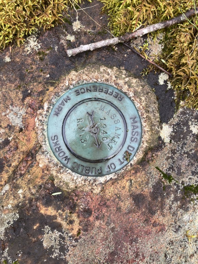 A brass surveying monument at the top of the mountain, set into bedrock there.